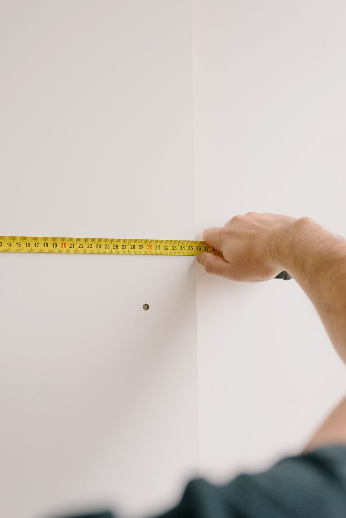 A hand holding a tape measure against a wall