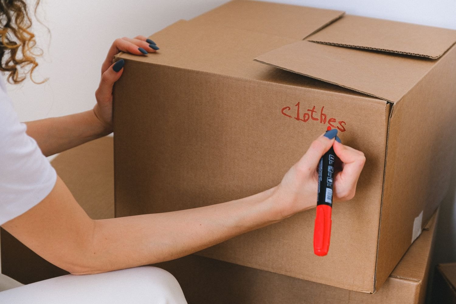 A woman labelling a box with a red marker