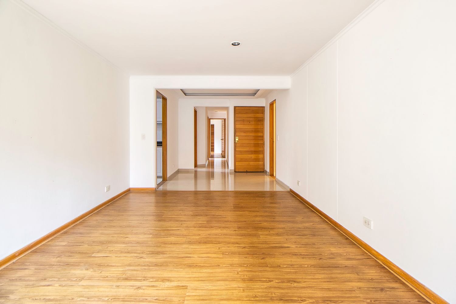 An empty room with a wooden floor and open doorways