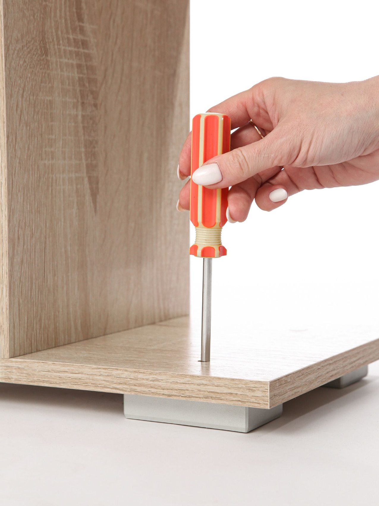 A hand tightening a furniture fitting with a screwdriver