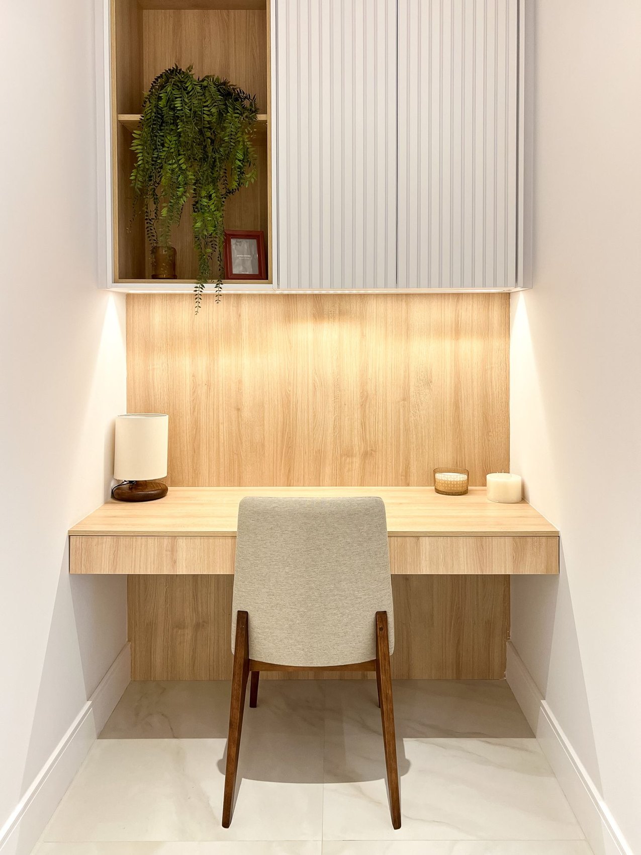 A wooden desk and chair in a workspace alcove