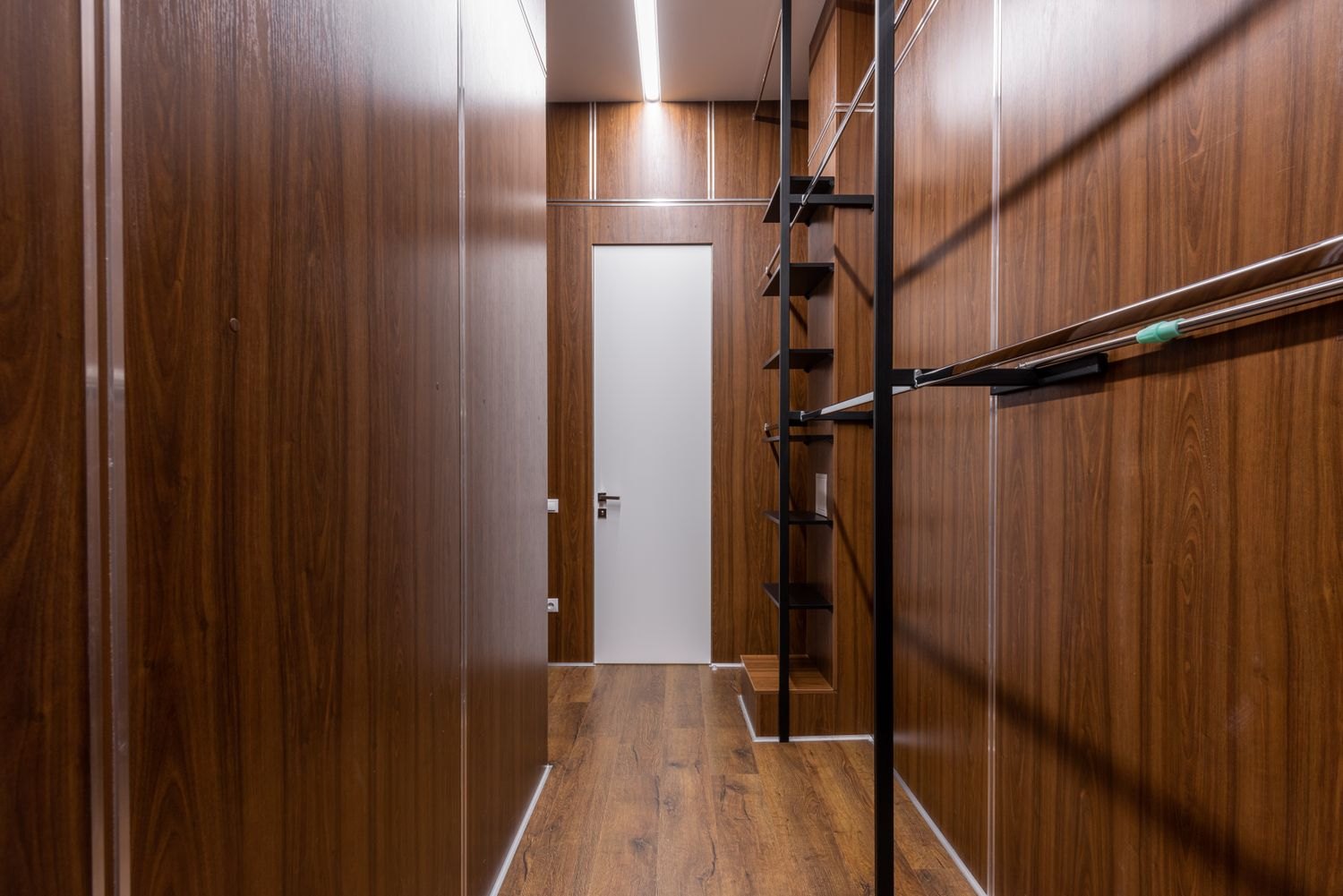 A narrow hallway with shelving along the side
