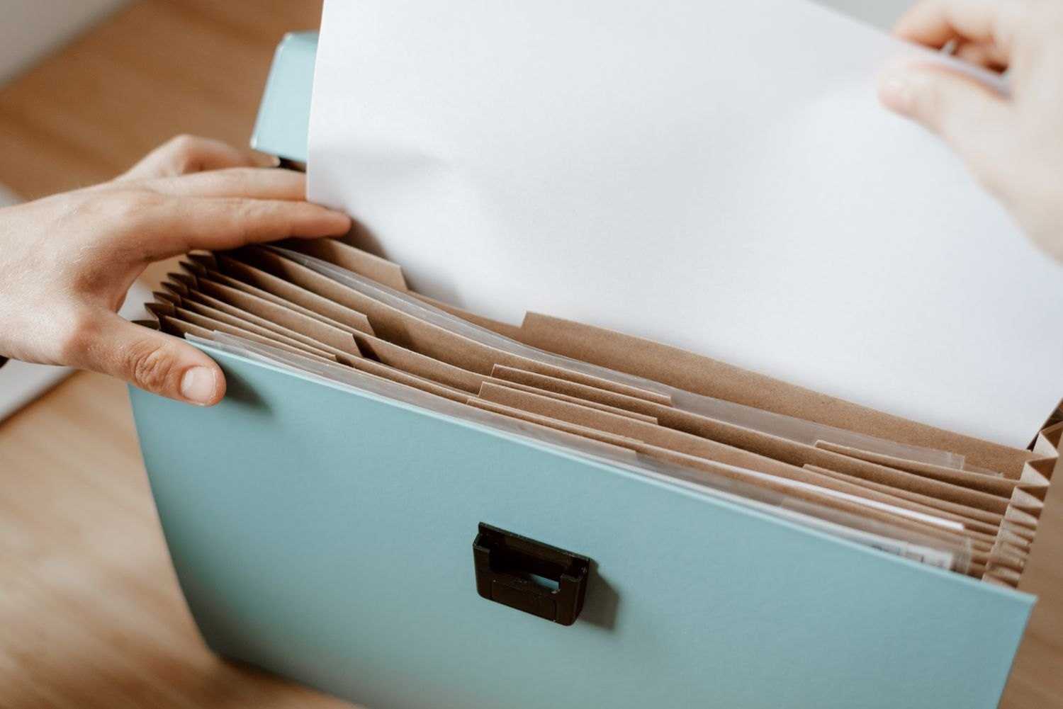 Hands organising papers in an expanding file