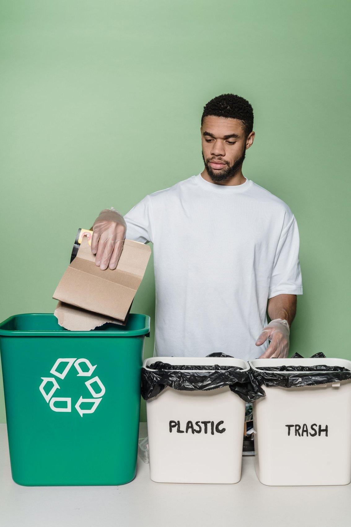 Ein Mann sortiert Pappe in einen Recyclingbehälter