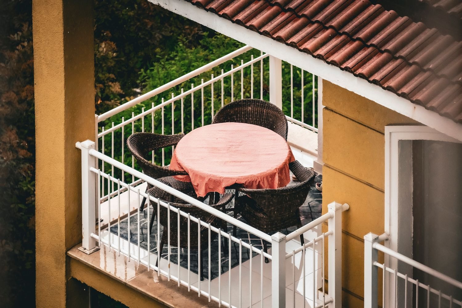 Ein kleiner Balkon mit Tisch und Stühlen bei nassem Wetter